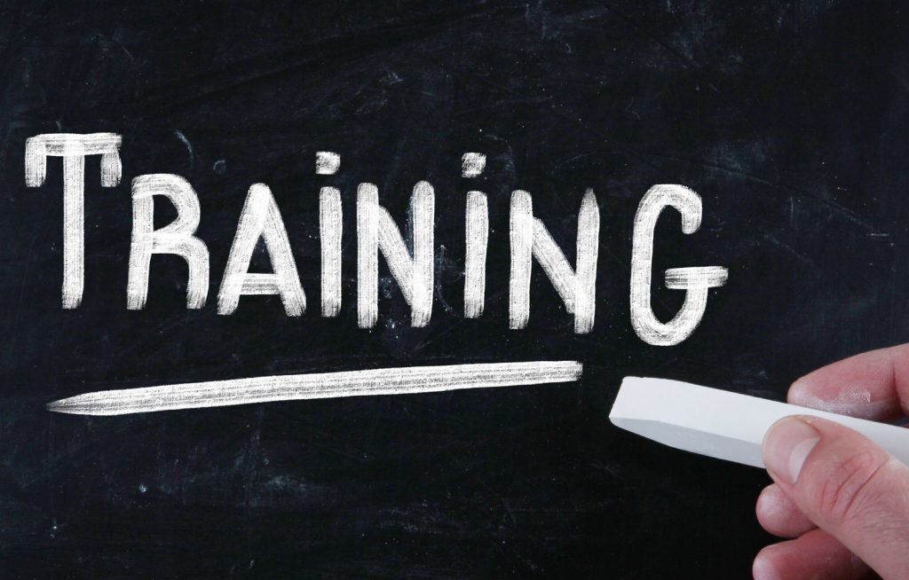 a hand writes the word training with chalk on a chalkboard, focusing on Why Contractor Training Matters