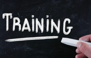 a hand writes the word training with chalk on a chalkboard, focusing on Why Contractor Training Matters